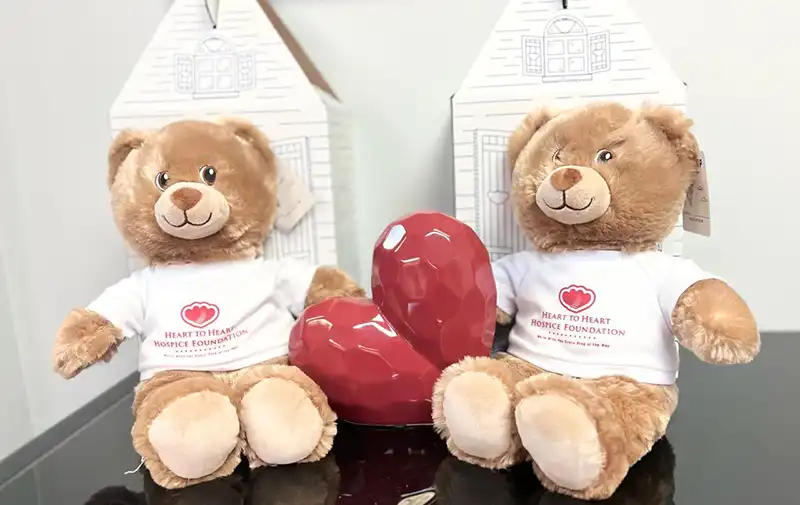Two HtoHH Foundation teddy bears sitting with a heart